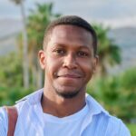 outdoor portrait of african american man with crossed arms looking at camera e1681376874850